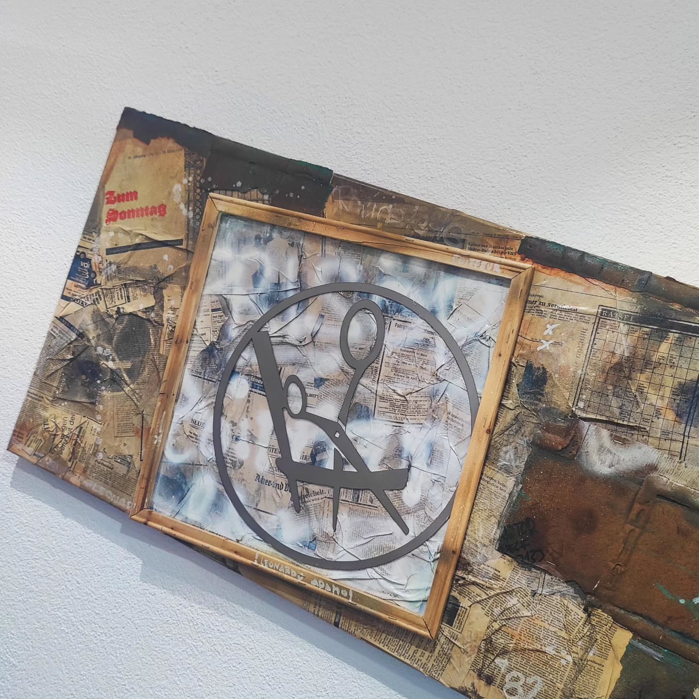 Eine kunstvolle Darstellung des Leonardo Adamo Firmenlogos, präzise aus Metall gefertigt und in eine Collage aus Zeitungen und modernen Texturen integriert, auf einer industriell anmutenden Rost-Optik-Leinwand.